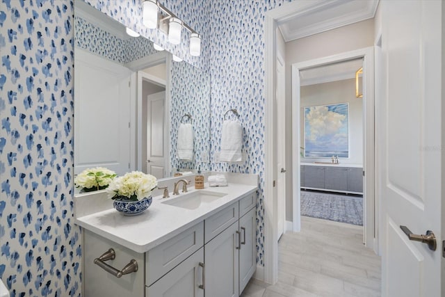 bathroom featuring baseboards, ornamental molding, vanity, and wallpapered walls