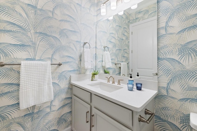 half bath with vanity and wallpapered walls