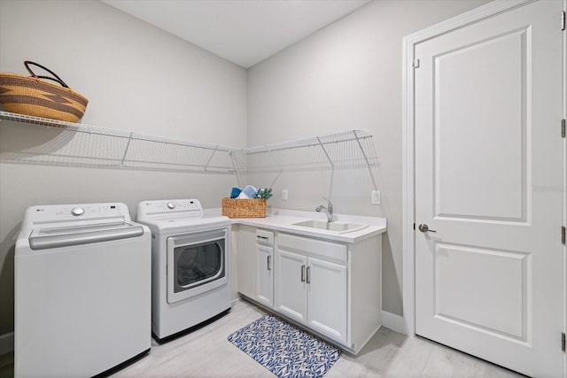 washroom featuring a sink, cabinet space, separate washer and dryer, and light wood-style flooring