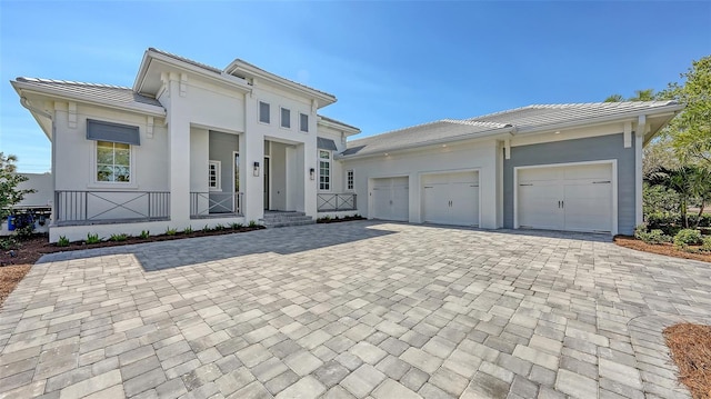 view of front facade featuring stucco siding, an attached garage, and decorative driveway