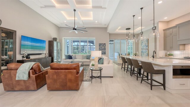 living room with coffered ceiling, beam ceiling, recessed lighting, ceiling fan, and a towering ceiling