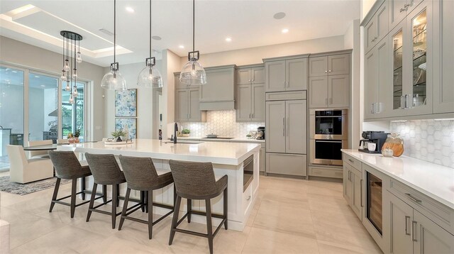 kitchen featuring paneled fridge, a breakfast bar area, stainless steel double oven, gray cabinets, and light countertops