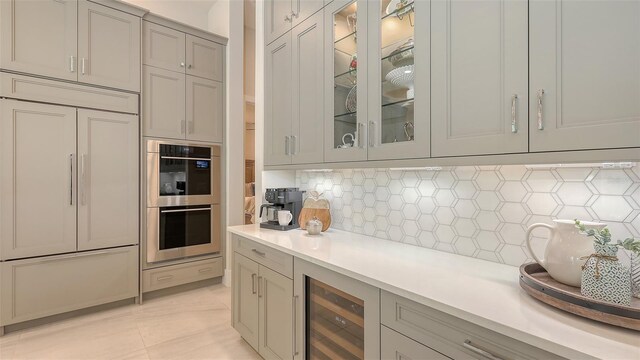 kitchen with stainless steel double oven, gray cabinetry, light countertops, wine cooler, and built in fridge