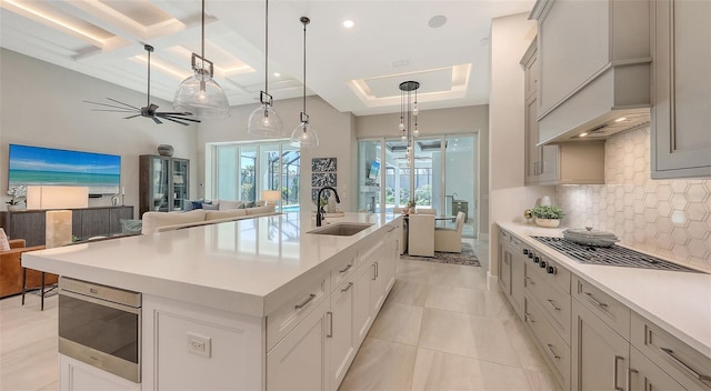 kitchen with light countertops, open floor plan, backsplash, and a sink