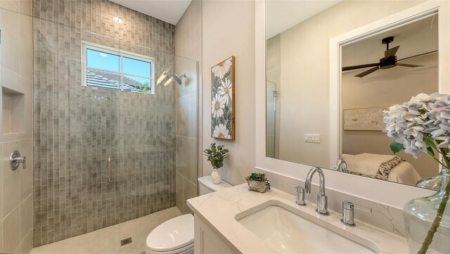 bathroom with vanity, toilet, ceiling fan, and tiled shower