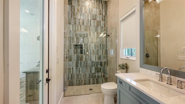 bathroom featuring tile patterned flooring, vanity, a shower stall, and toilet