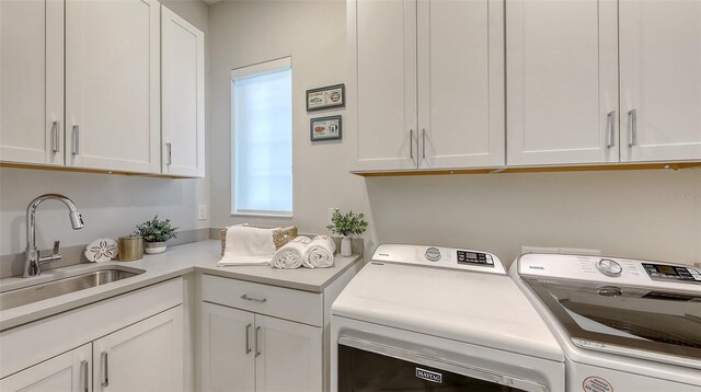 clothes washing area featuring a sink, cabinet space, and separate washer and dryer