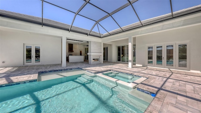 view of pool featuring a pool with connected hot tub, a lanai, french doors, a patio area, and a ceiling fan