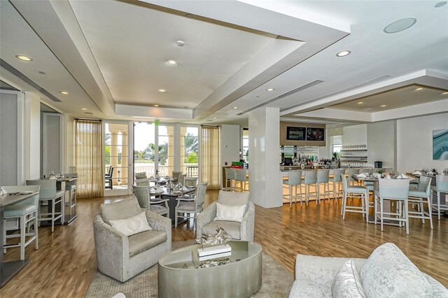 living area featuring recessed lighting, a tray ceiling, and wood finished floors