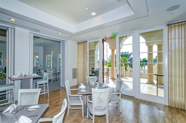 dining space with recessed lighting, french doors, a tray ceiling, and wood finished floors