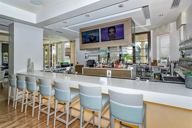 bar featuring indoor wet bar, visible vents, a healthy amount of sunlight, and wood finished floors