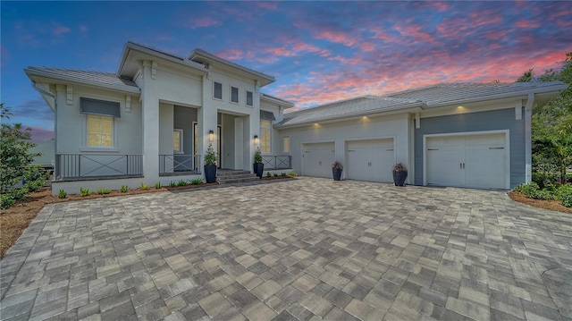 8348 Catamaran Cir, Lakewood Ranch, FL 34202 - view of front of house with a tiled roof, decorative driveway, an attached garage, stucco siding, and a porch