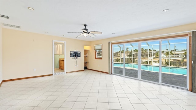 empty room featuring light tile patterned floors, visible vents, baseboards, and a ceiling fan