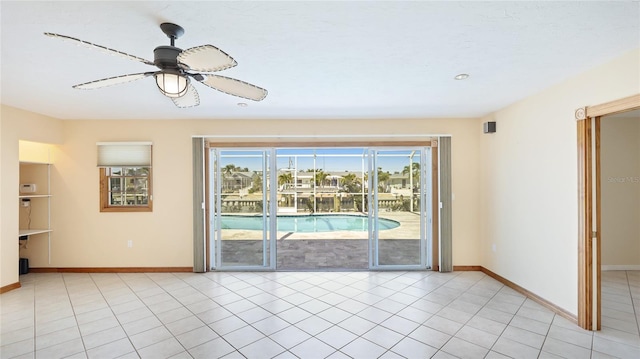 spare room featuring light tile patterned flooring, a ceiling fan, and baseboards