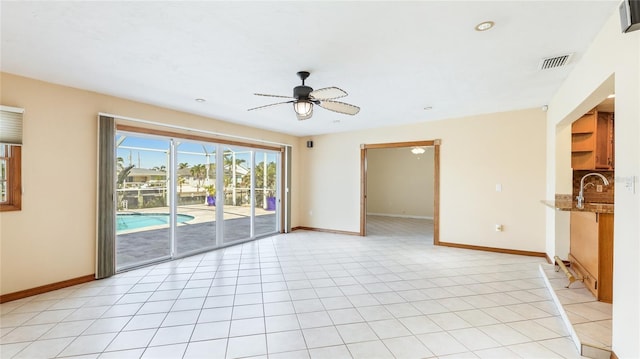 spare room featuring light tile patterned flooring, a ceiling fan, visible vents, and baseboards