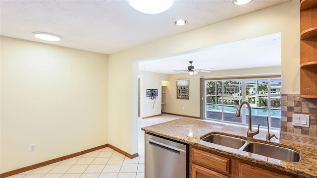 kitchen with brown cabinetry, light stone countertops, open shelves, a sink, and dishwasher