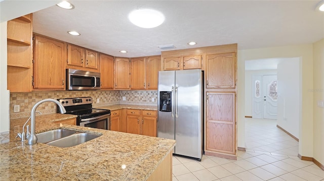 kitchen with a sink, open shelves, light stone counters, tasteful backsplash, and stainless steel appliances