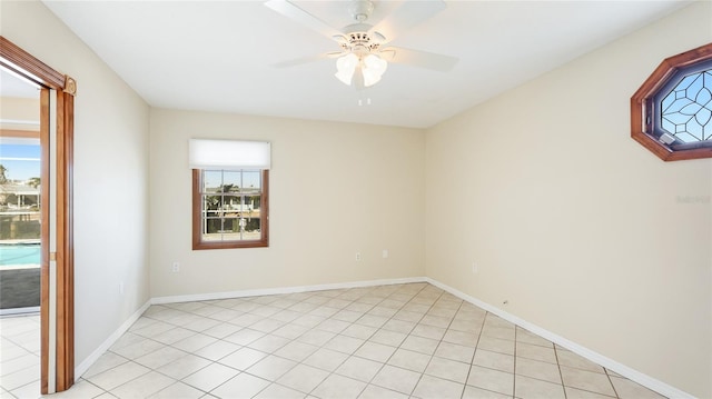 spare room with light tile patterned floors, ceiling fan, and baseboards