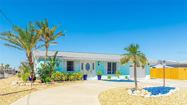 ranch-style house featuring concrete driveway, fence, a garage, and stucco siding