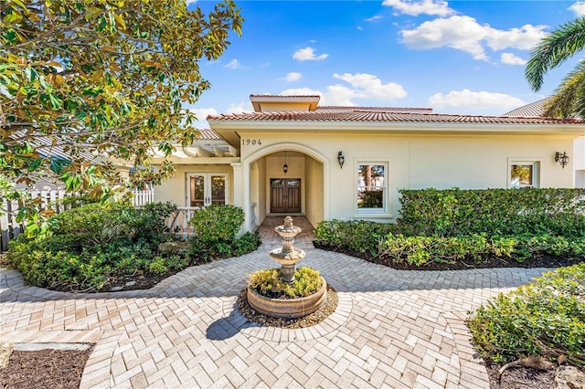 mediterranean / spanish-style home featuring stucco siding, french doors, and a tile roof