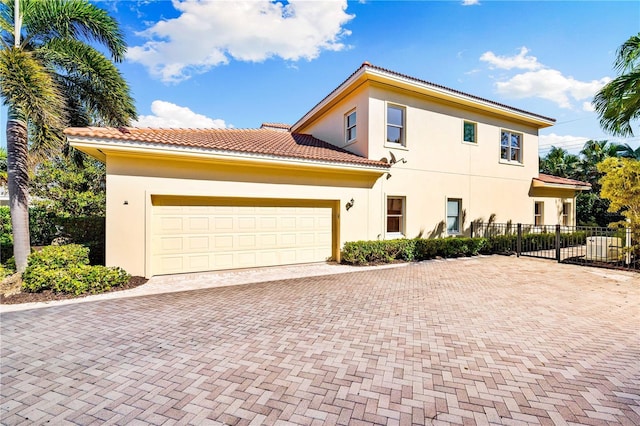 view of front of house featuring stucco siding, decorative driveway, an attached garage, and fence