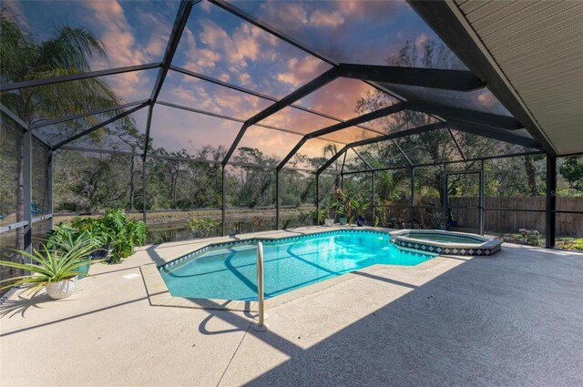 1127 133rd St E, Bradenton, FL 34212 - pool at dusk with a pool with connected hot tub, glass enclosure, fence, and a patio area