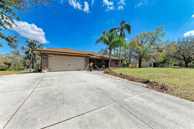 1127 133rd St E, Bradenton, FL 34212 - ranch-style home with a front lawn, an attached garage, brick siding, and concrete driveway