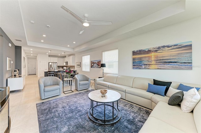 living area featuring visible vents, a ceiling fan, a tray ceiling, recessed lighting, and light tile patterned floors