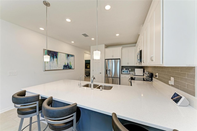 kitchen featuring visible vents, a sink, appliances with stainless steel finishes, a peninsula, and decorative backsplash