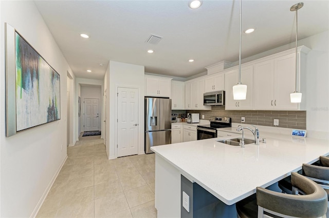 kitchen with a peninsula, a sink, light countertops, appliances with stainless steel finishes, and tasteful backsplash