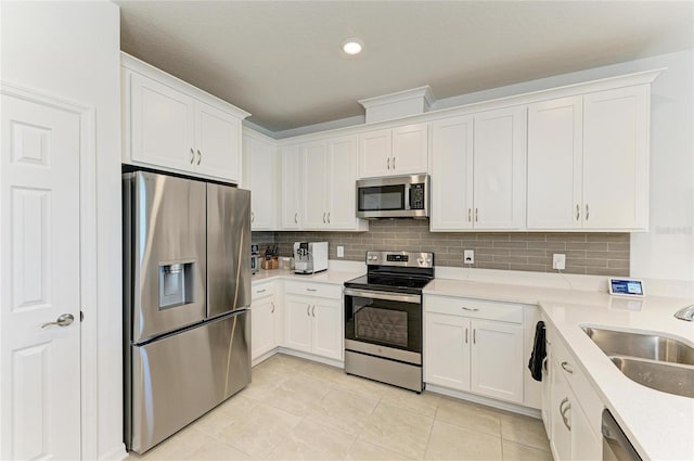 kitchen with a sink, stainless steel appliances, light countertops, white cabinetry, and backsplash