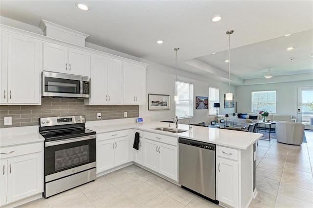 kitchen featuring a peninsula, a sink, stainless steel appliances, light countertops, and open floor plan