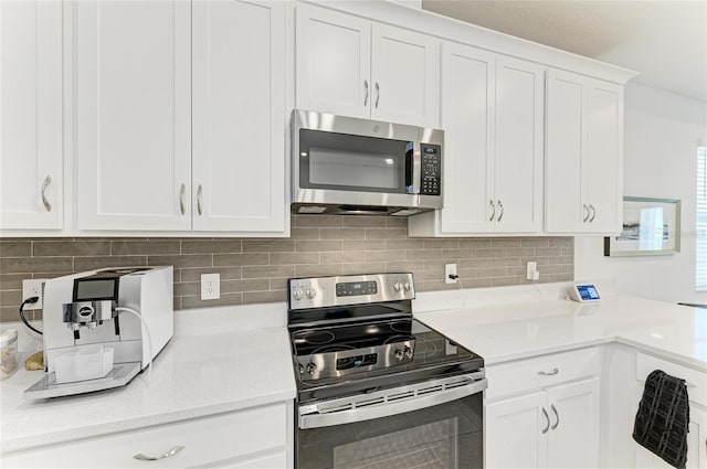 kitchen with light stone countertops, backsplash, appliances with stainless steel finishes, and white cabinets