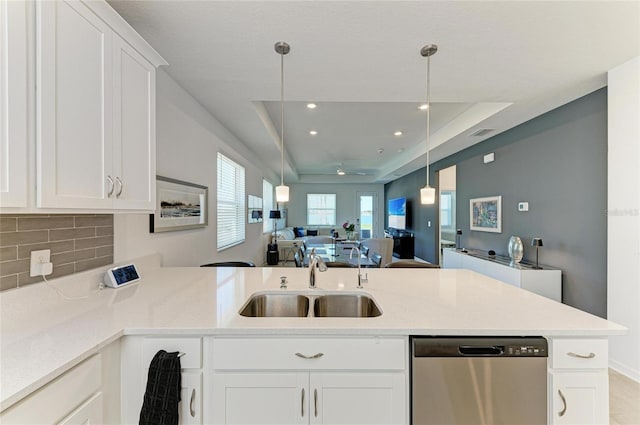 kitchen featuring a peninsula, a sink, dishwasher, a raised ceiling, and open floor plan