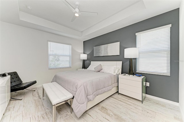 bedroom featuring baseboards, a raised ceiling, and wood finished floors