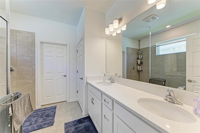 bathroom featuring double vanity, tiled shower, visible vents, and a sink