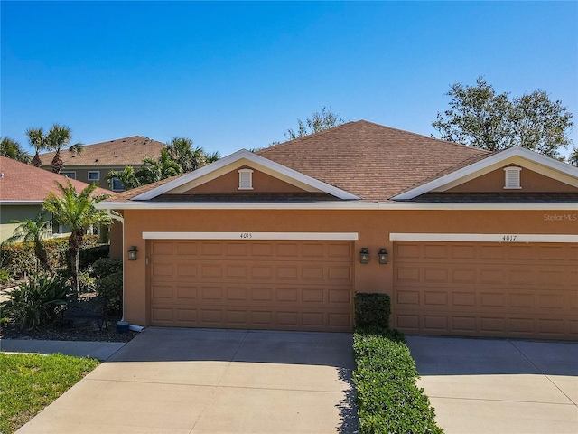 view of front of property with a shingled roof, concrete driveway, and stucco siding