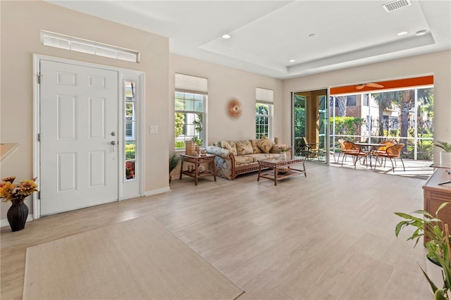 entrance foyer featuring a tray ceiling, visible vents, and light wood finished floors