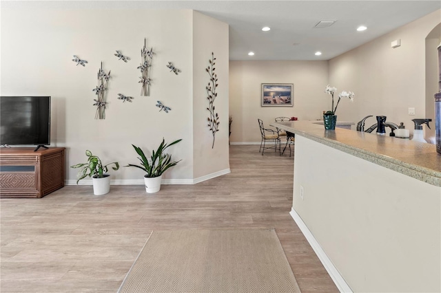 interior space with recessed lighting, baseboards, arched walkways, and light wood finished floors