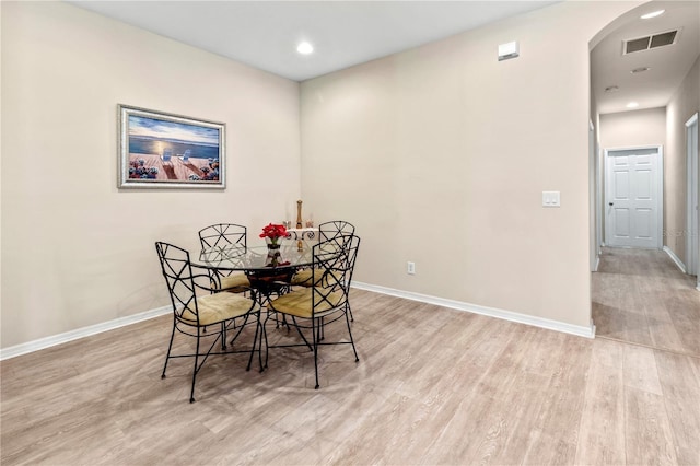 dining room featuring baseboards, arched walkways, visible vents, and light wood-type flooring