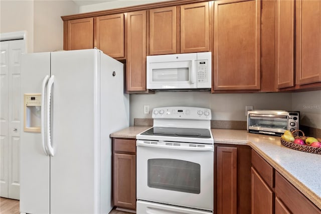 kitchen featuring white appliances, brown cabinets, a toaster, and light countertops