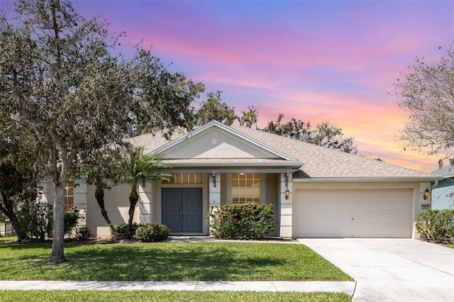 view of front of house with a shingled roof, concrete driveway, a front yard, stucco siding, and a garage