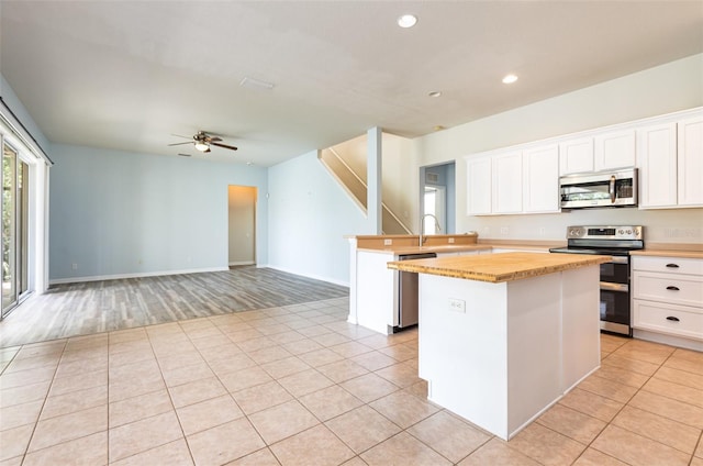 kitchen featuring light tile patterned floors, a kitchen island, stainless steel appliances, and a ceiling fan