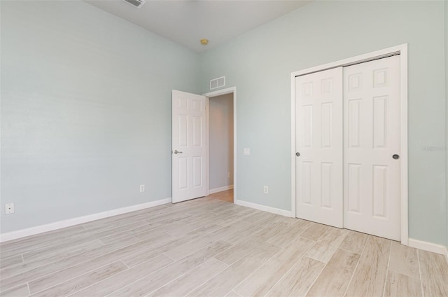 unfurnished bedroom with light wood-style flooring, baseboards, visible vents, and a closet