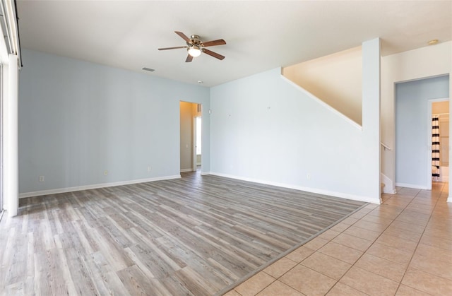 unfurnished room featuring visible vents, wood finished floors, ceiling fan, and stairs