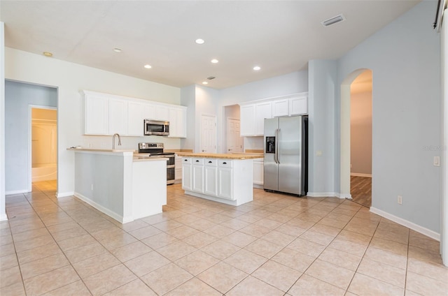 kitchen with visible vents, recessed lighting, appliances with stainless steel finishes, arched walkways, and white cabinetry