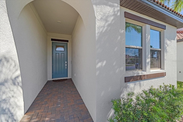 doorway to property featuring stucco siding and a tiled roof