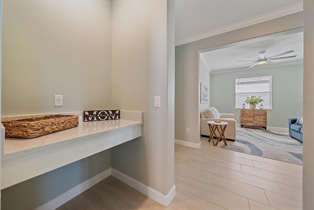 interior space featuring baseboards, a ceiling fan, and crown molding