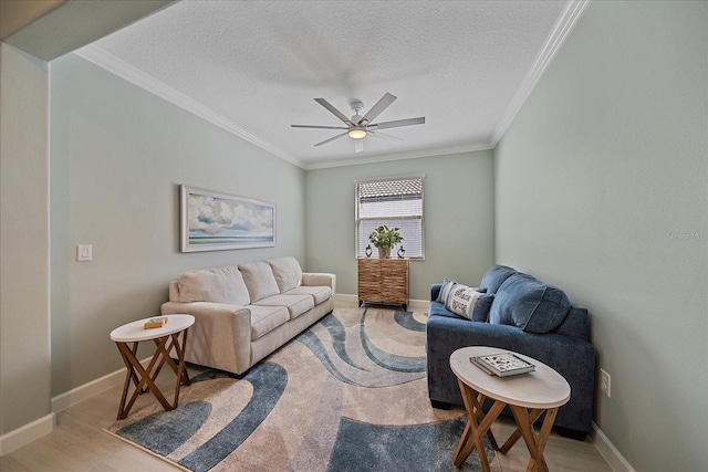 living room featuring a ceiling fan, a textured ceiling, light wood-style floors, crown molding, and baseboards