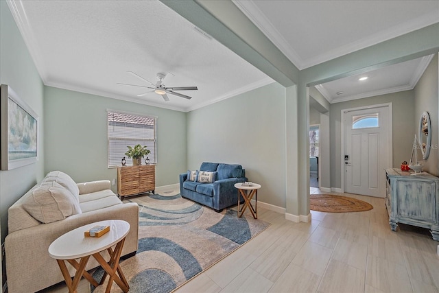 living area with crown molding, a ceiling fan, and baseboards